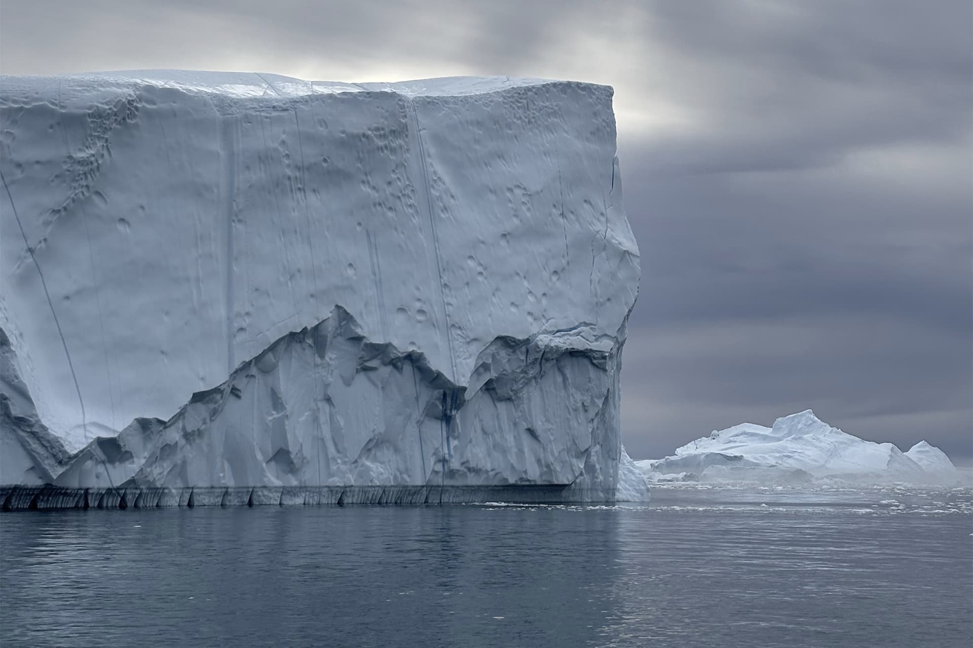 A large glacier stands tall above the ocean.