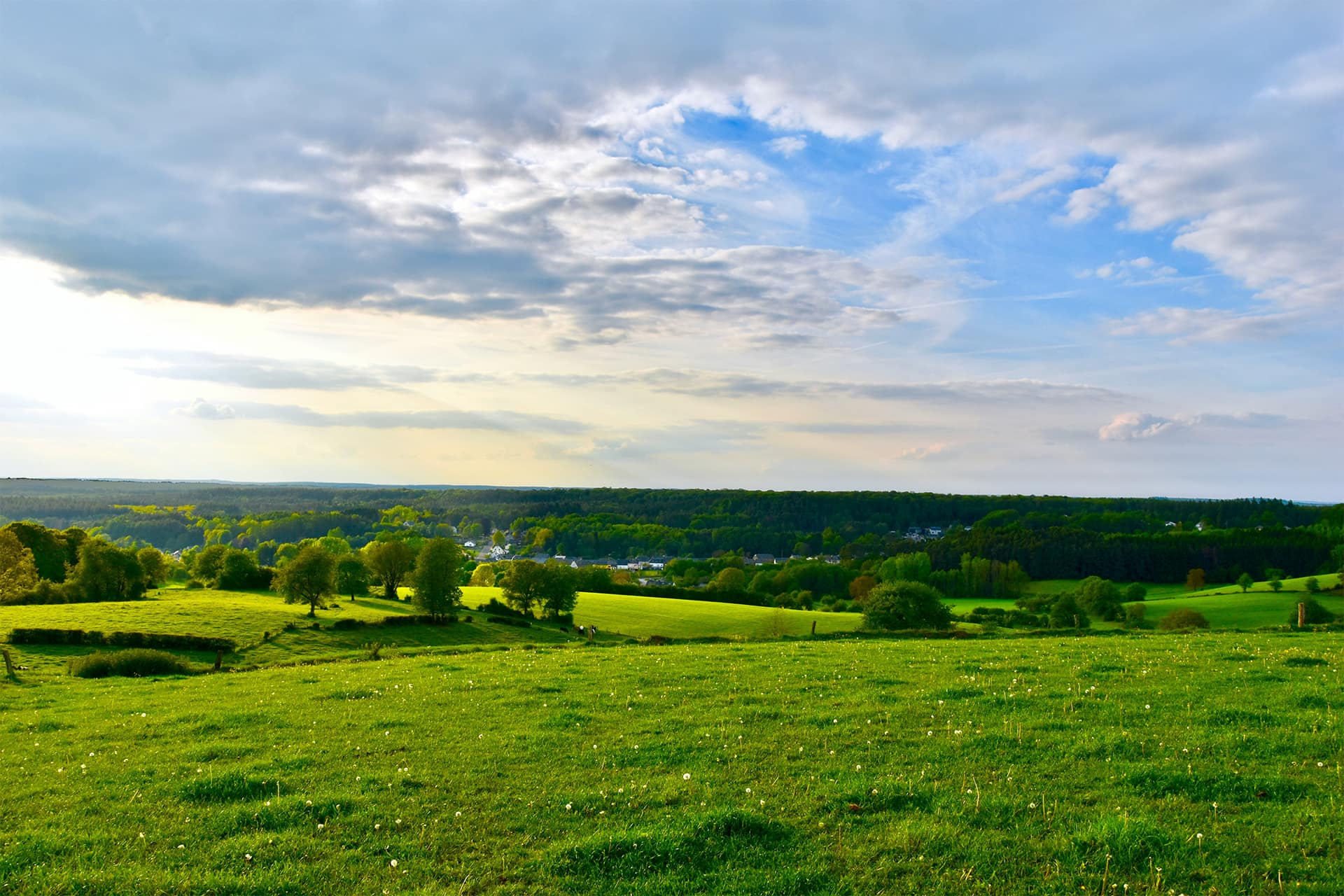 Sunny skies over a green field in Chatillon, Belgium.